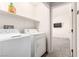Efficient laundry room includes washer, dryer, storage shelf, and access to bedroom with mounted TV at 9333 Leaping Deer Pl # 102, Las Vegas, NV 89178