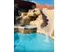 Close-up of a luxurious backyard pool showcasing a rock waterfall, spa, and a thrilling water slide at 5301 Fairbranch Ln, Las Vegas, NV 89135