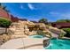 A captivating view of the pool with a rock waterfall, spa, and slide, surrounded by lush greenery at 5301 Fairbranch Ln, Las Vegas, NV 89135