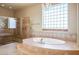 Luxurious bathroom with a large soaking tub, walk-in shower, and a decorative glass block window at 3301 Rodeo Ave, Pahrump, NV 89048