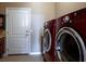 Modern laundry room featuring red washer and dryer units, alongside a convenient utility sink at 3301 Rodeo Ave, Pahrump, NV 89048