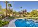 Sparkling pool surrounded by lush landscaping and mature palm trees, creating a private backyard oasis at 1002 Prestige Meadows Pl, Henderson, NV 89052