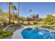 Private pool with well-maintained landscaping and clear blue skies, surrounded by tall palm trees at 1002 Prestige Meadows Pl, Henderson, NV 89052