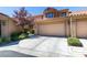 Tan stucco townhouse with a one-car garage and landscaping at 7132 Mission Hills Dr, Las Vegas, NV 89113