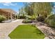 Well-maintained backyard with trees, lush landscaping, and a covered patio at 1629 Black Fox Canyon Rd, Henderson, NV 89052