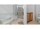 Bathroom featuring a soaking tub, glass-enclosed shower, and neutral-toned tile at 1629 Black Fox Canyon Rd, Henderson, NV 89052