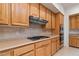 Kitchen featuring modern stainless appliances, wooden cabinets, and a stone backsplash at 1629 Black Fox Canyon Rd, Henderson, NV 89052
