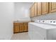 Bright laundry room features wooden cabinets and a white washer and dryer set at 1629 Black Fox Canyon Rd, Henderson, NV 89052