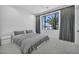 Modern bedroom with a plush bed, gray accents, and a large window with a palm tree view at 9760 Solar Ave, Las Vegas, NV 89149