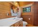 Small bathroom with wood walls, a white vanity, and a window at 2196 Via Dulcedo St, Mount Charleston, NV 89124