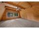 Spacious carpeted bedroom with wood-paneled walls, ceiling fan, and bright windows overlooking the natural landscape at 2196 Via Dulcedo St, Mount Charleston, NV 89124