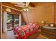 Cozy bedroom with wood walls, a red quilt, and access to a deck at 2196 Via Dulcedo St, Mount Charleston, NV 89124