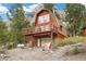 Two-story home with a garage and a balcony, nestled among lush greenery and views of the mountain at 2196 Via Dulcedo St, Mount Charleston, NV 89124