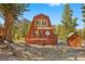 Cabin-style home with a wooden deck, nestled among lush greenery and includes a storage shed at 2196 Via Dulcedo St, Mount Charleston, NV 89124