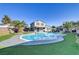 Kidney-shaped pool surrounded by lush grass and palm trees at 4474 Dawley Ct, Las Vegas, NV 89104