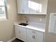 Bright laundry room with white cabinets and a new stainless steel sink at 9886 Belikove Manor Ave, Las Vegas, NV 89178