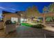 The backyard patio at night features a built-in BBQ, pavers, seating, and lush landscaping under soft lighting at 17 Winding Rd, Henderson, NV 89052