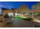 Outdoor kitchen overlooks backyard at dusk, featuring pool, landscaping, and seating at 17 Winding Rd, Henderson, NV 89052