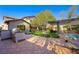This beautiful backyard has a built-in BBQ, pavers, seating, lush landscaping, and a pergola near the pool at 17 Winding Rd, Henderson, NV 89052