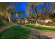Evening view of backyard featuring a putting green, pergola, seating, and lush landscaping at 17 Winding Rd, Henderson, NV 89052