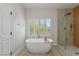 Freestanding soaking tub and glass enclosed shower with wood look tile at 17 Winding Rd, Henderson, NV 89052
