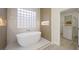 Elegant bathroom featuring a standalone tub, glass block window, and access to a walk-in closet at 17 Winding Rd, Henderson, NV 89052