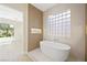 Luxurious bathroom with standalone tub, unique glass block window, and modern tile accents at 17 Winding Rd, Henderson, NV 89052