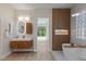 This modern bathroom features double sinks, a soaking tub, a walk-in shower, and warm elegant decor at 17 Winding Rd, Henderson, NV 89052