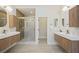 Sleek bathroom featuring double sinks, wooden vanity, glass shower, and modern lighting fixtures at 17 Winding Rd, Henderson, NV 89052