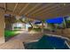 Backyard with a pool and pergola, enhanced by landscape lighting at dusk at 17 Winding Rd, Henderson, NV 89052