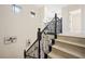 Elegant staircase featuring light wood steps, a black iron railing, and a modern chandelier at 17 Winding Rd, Henderson, NV 89052