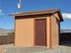 Exterior view of a backyard shed featuring brown wood paneling and a dark brown door at 1120 W Gray Fox Way, Pahrump, NV 89048