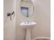 Small bathroom with pedestal sink and round mirror at 4327 Melrose Abbey Pl, Las Vegas, NV 89141