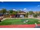 Spacious backyard featuring artificial turf, a red brick patio, and mature trees at 16 Cerrito St, Blue Diamond, NV 89004