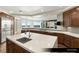 A kitchen features an island, stainless appliances, wood cabinets, white counters, and large windows overlooking a city view at 9101 Alta Dr # 1202, Las Vegas, NV 89145