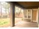 View of a covered back patio with a door and large window looking out to a grassy backyard with mature trees at 9809 Miss Peach Ave, Las Vegas, NV 89145