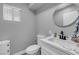 Modern bathroom with a gray wall, round mirror, and marble countertops at 7135 Polaris Ave, Las Vegas, NV 89118