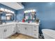 Bright bathroom with white cabinets, marble countertops, and a soaking tub beneath a blue accent wall at 7135 Polaris Ave, Las Vegas, NV 89118