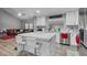 Modern open kitchen and living room with white cabinets, marble countertops, stainless steel appliances and breakfast bar at 7135 Polaris Ave, Las Vegas, NV 89118