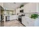 Bright kitchen features white cabinets, stainless steel appliances, stone countertops, and a wood-look floor at 10315 Premia Pl, Las Vegas, NV 89135