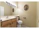 Cozy bathroom with a wood vanity, large mirror, toilet, and decorative portrait on the neutral wall at 1214 Country Club Dr, Laughlin, NV 89029