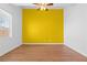 A modern bedroom with wood floors, a ceiling fan and a bright yellow accent wall at 3665 Bella Legato Ave, North Las Vegas, NV 89081