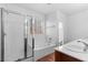 This main bathroom showcases a tub with glass shower, a single vanity, and wood-look floors at 3665 Bella Legato Ave, North Las Vegas, NV 89081