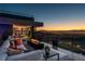 Modern patio with comfortable seating and a fire pit overlooking the city skyline at dusk at 685 Dragon Peak Dr, Henderson, NV 89012