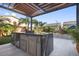 Modern outdoor kitchen with stainless steel appliances and granite countertops under a pergola at 8620 Grove Mill Ct, Las Vegas, NV 89139