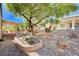 Landscaped backyard featuring mature trees, decorative rocks, and a covered patio for outdoor enjoyment at 7457 Widewing Dr, North Las Vegas, NV 89084