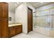 Bright bathroom features a bathtub with glass doors, dual sinks, and dark wooden cabinetry at 1309 Imperia Dr, Henderson, NV 89052