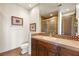 Bathroom featuring a decorative vanity with stone countertop, a large mirror, and tiled shower with glass door at 1309 Imperia Dr, Henderson, NV 89052