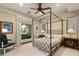 Comfortable bedroom with a canopy bed, neutral tones, and natural light streaming in from a garden view window at 1309 Imperia Dr, Henderson, NV 89052
