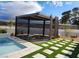 The pergola offers a relaxing retreat, complemented by a pool and decorative stone and grass accents at 8780 Haven St, Las Vegas, NV 89123